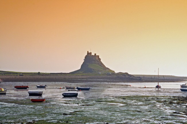 Lindisfarne_castle_at_sunset,_boats_at_low_tide
